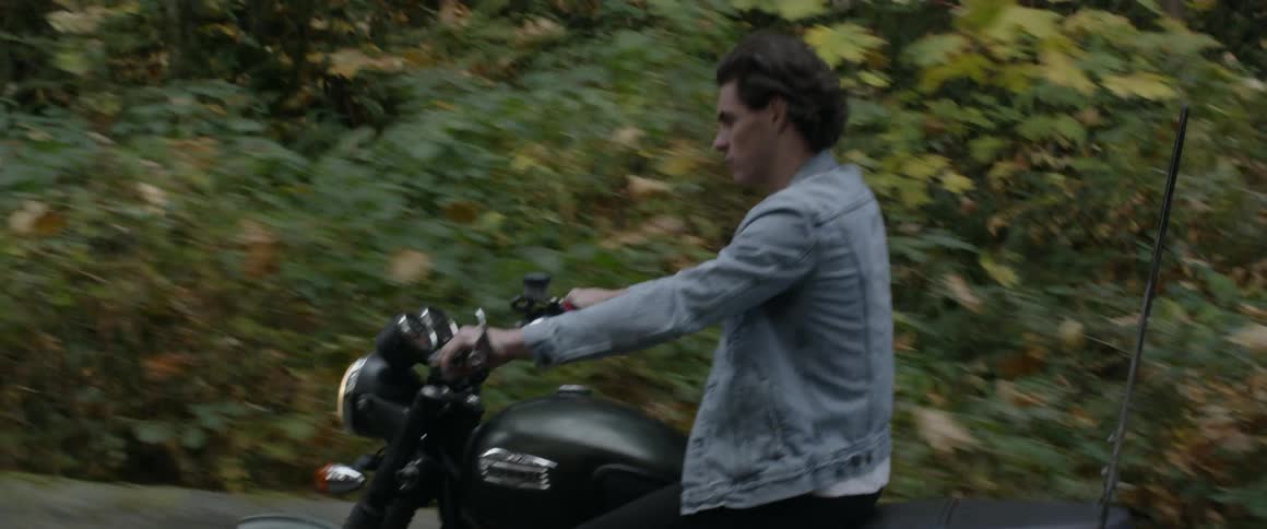 A man rides a motorcycle on the woodsy road