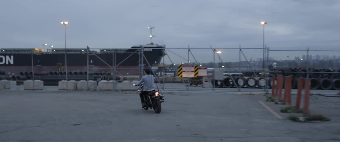 A man rides a motorcycle to the docks