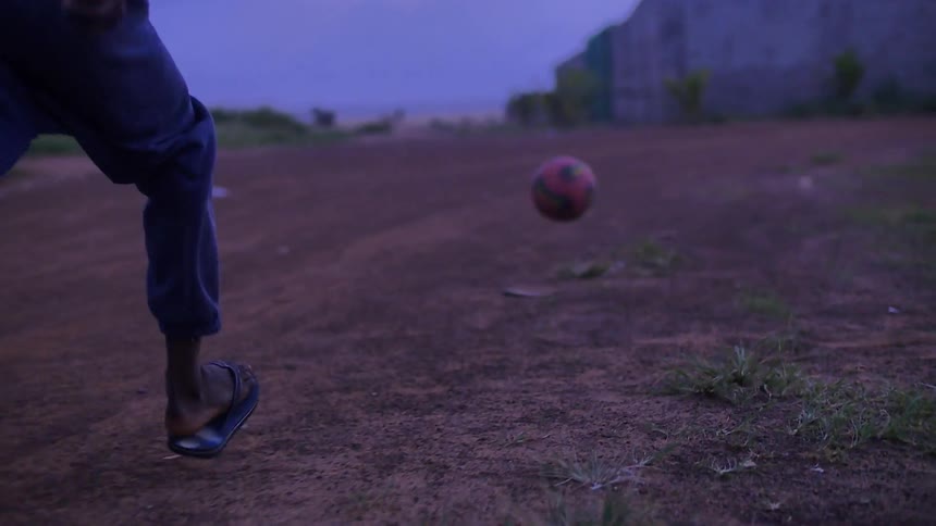 A child kicks a soccer ball in a rural area
