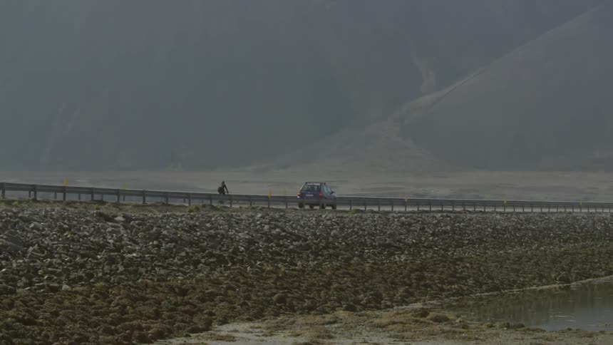 A vehicle and bicyclist travel on a rural road