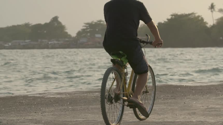 A bicyclist pedals on a beach