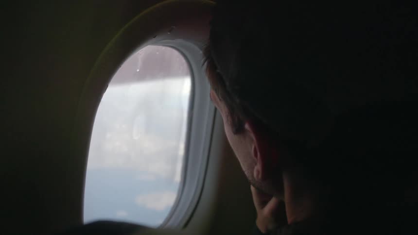 A man looking out of an airplane window