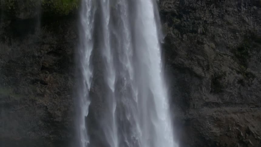Water falls from a high cliff in four separate waterfalls
