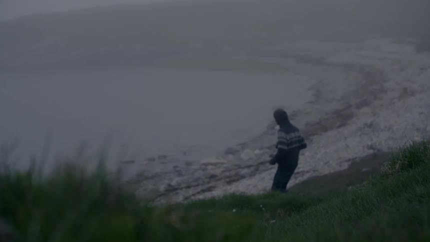 A man descends a hill towards a beach