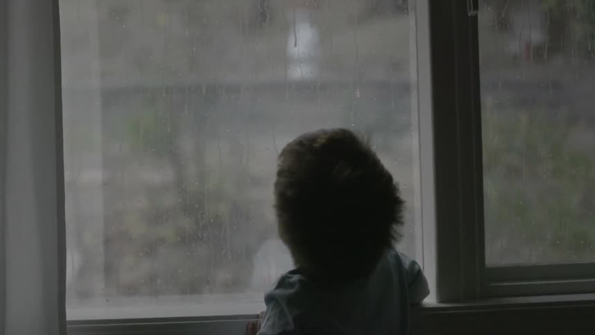 Person watching the rain outside through the window