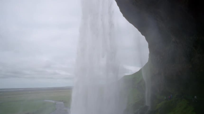 Water gushes over a cliff into a body of water below