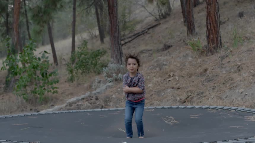A child jumps on a trampoline in the day time