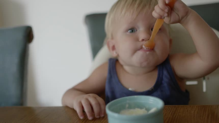 A baby eats a bowl of ice cream