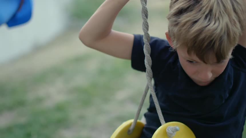 A boy rotates on an outdoor swing