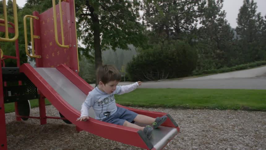 A toddler slides down a slide in a playground