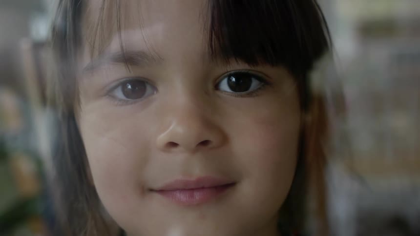 Young girl touching windowpane while slightly grinning