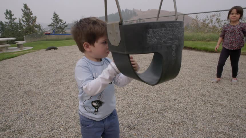 A kid playing with a swing