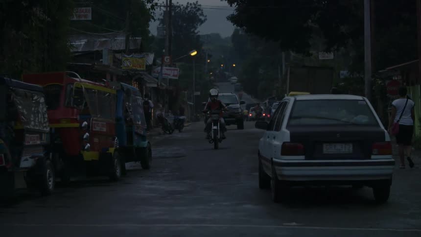 Vehicles drive down a town road at night