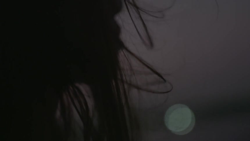 A woman is standing outdoors on a windy night