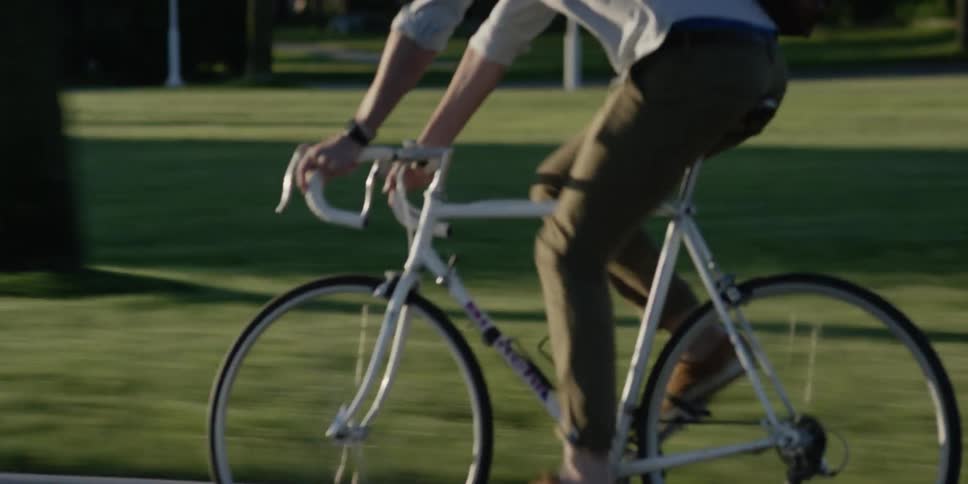 A man pedals his bicycle quickly down the street on a sunny day