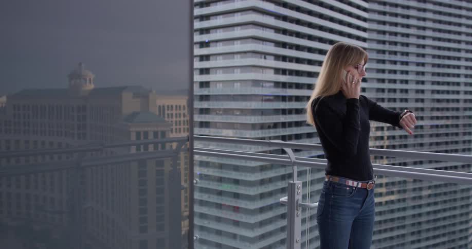 A woman talks on the phone outside on the balcony