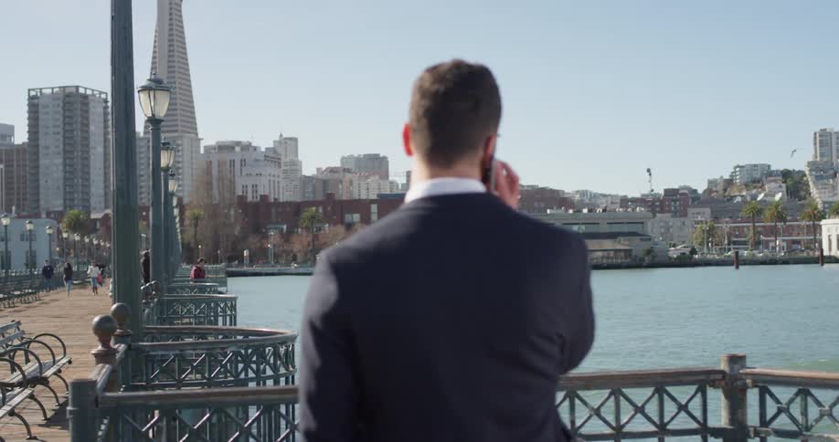 A man in a suit looks out towards the water