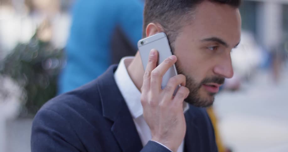 Man smiles and talks on a cell phone outside