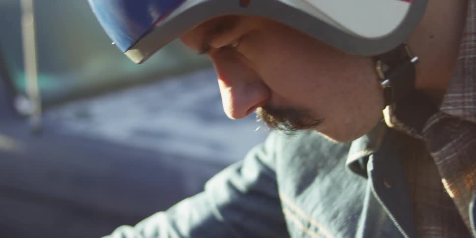 A mustached, brunette man revving the throttle on a motorcycle