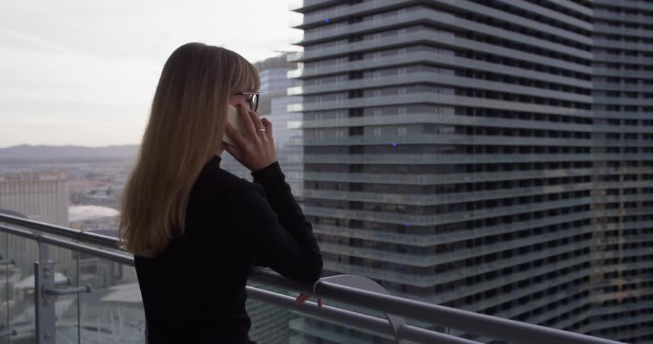 A woman uses her phone on the balcony