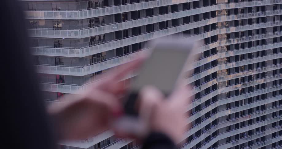 A person uses a smartphone on an apartment balcony