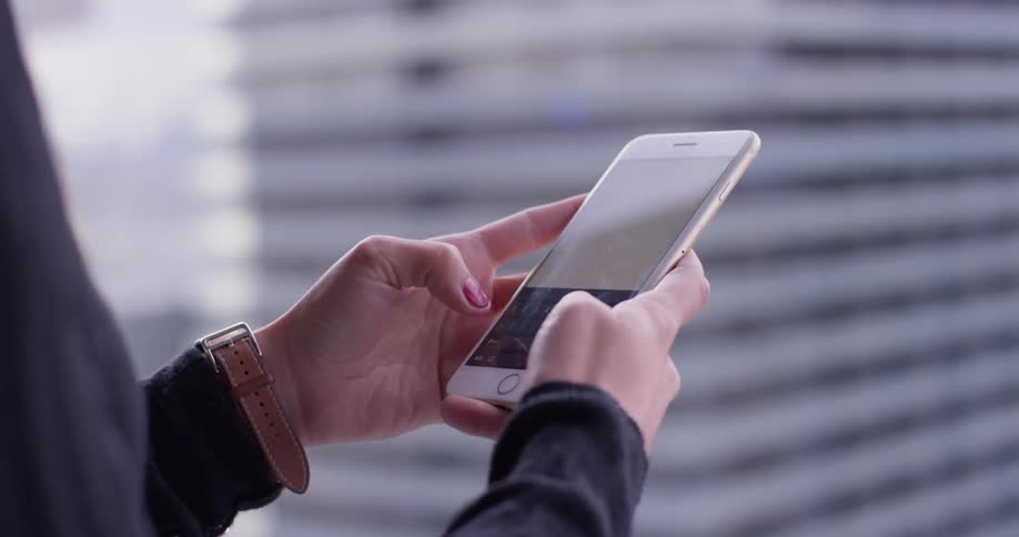 A woman types on her phone on the balcony