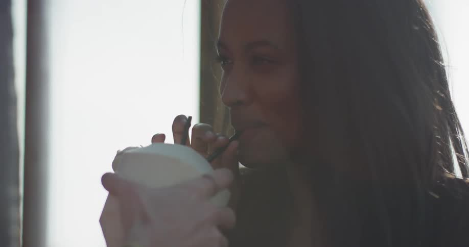 A woman takes a sip from a coconut