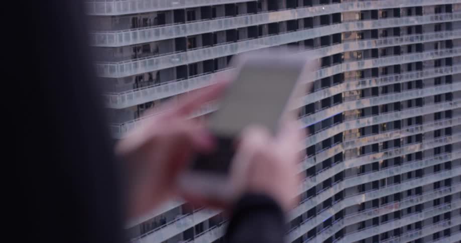 A woman uses her phone on the balcony