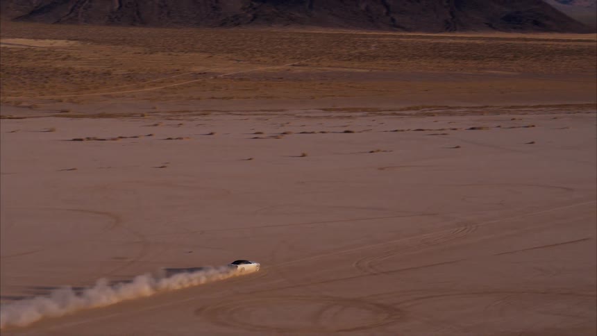 Car travels over the sandy land under a blue sky