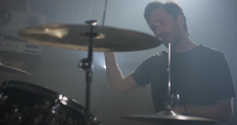 A man plays drums in a garage