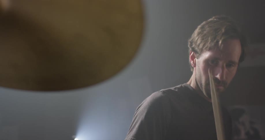 Man drums on a drum set and turns his head