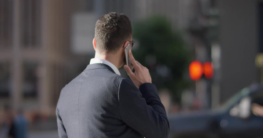 A man in a suit uses his phone outside in the city