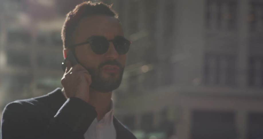 A man talks on the phone on a city sidewalk