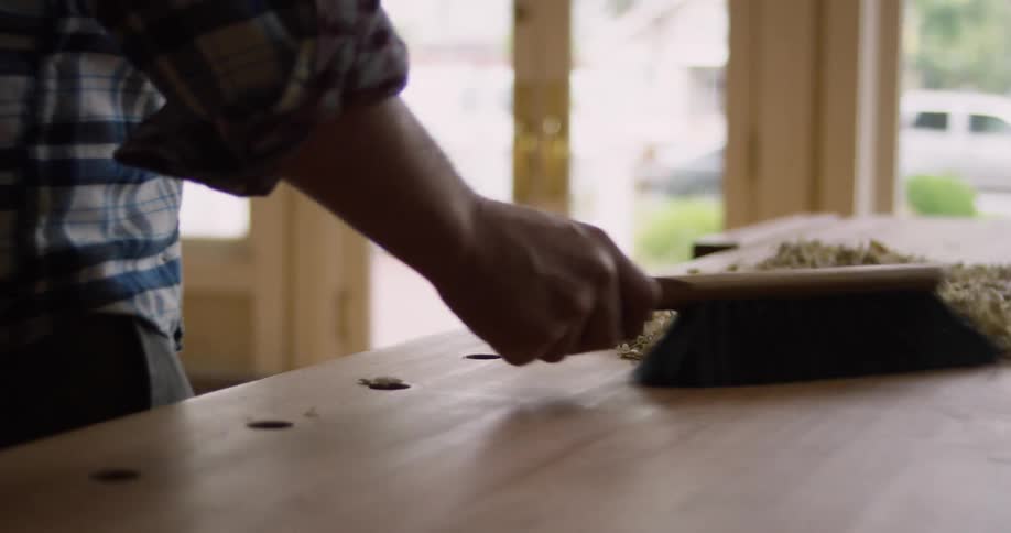 A man sweeping wood shavings from a workbench