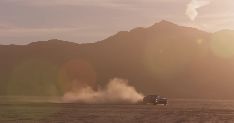 A car spins in circles in a dirt field surrounded by mountains