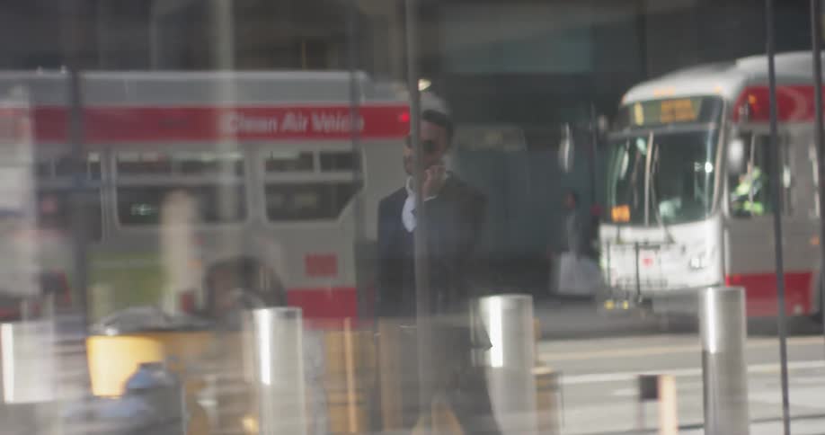 Man talks on his cellphone as he walks on the city sidewalk