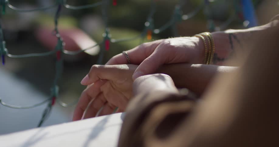 Man and woman hold hands as they stand near the fence