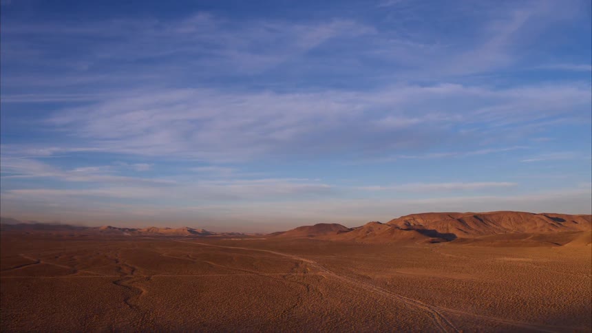 Wispy clouds over rocky hilly desert