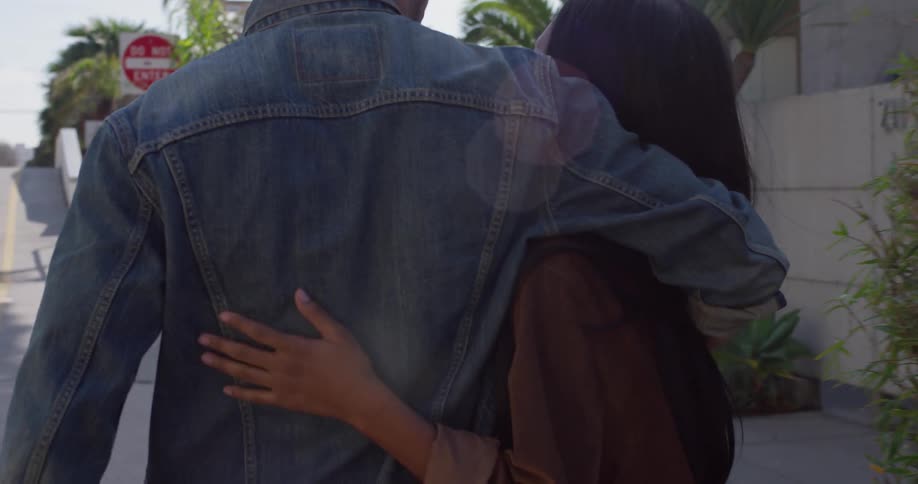 A man and woman hug while walking on a city street