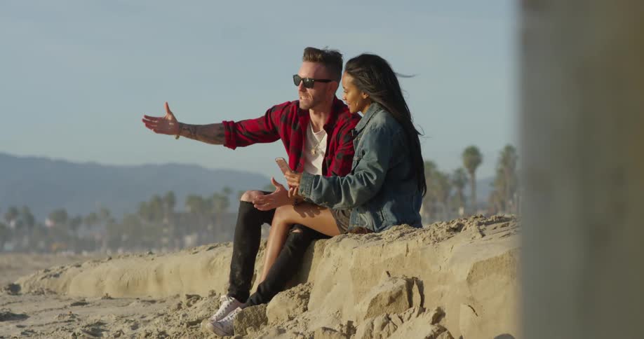 A man and woman sit together and look at her phone