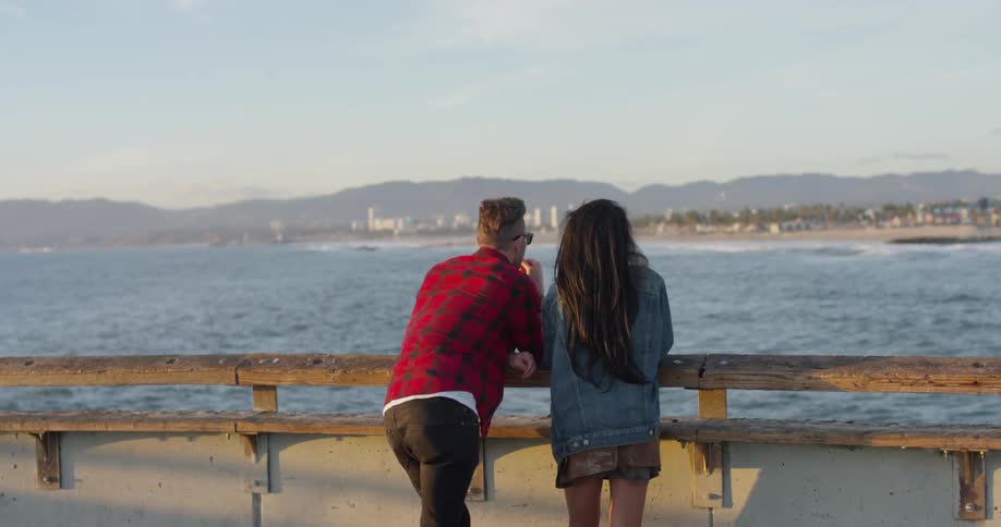 A man and woman stand on an ocean pier