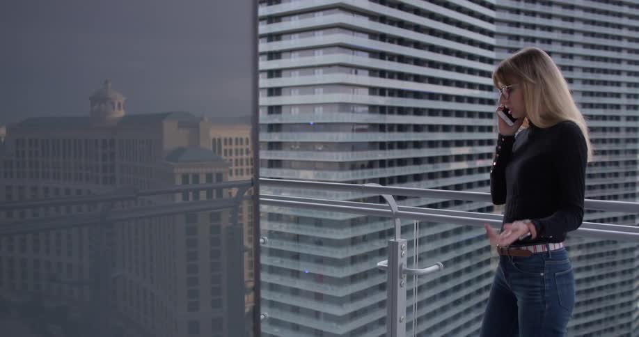 A man uses a phone outside on the balcony