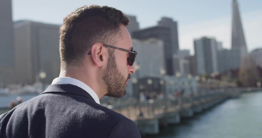 Man wearing sunglasses looks out at the lake in the city