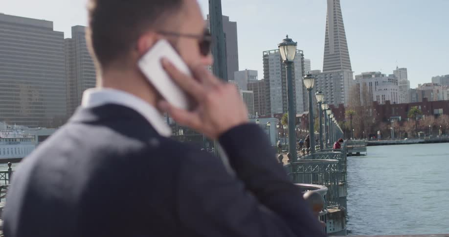 Man talks on a phone standing by a river