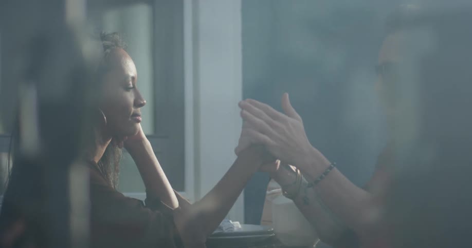 A woman and man hold hands at an outdoor table