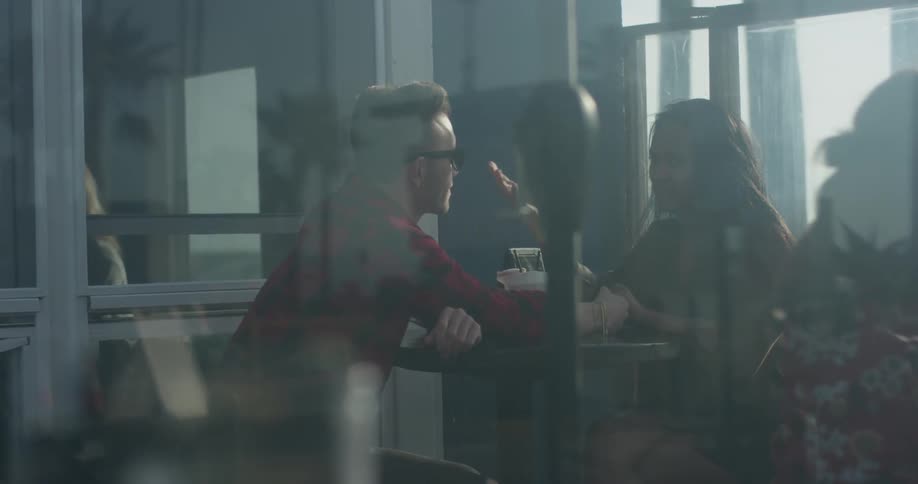 Man and woman sit at a table in a coffee shop talking