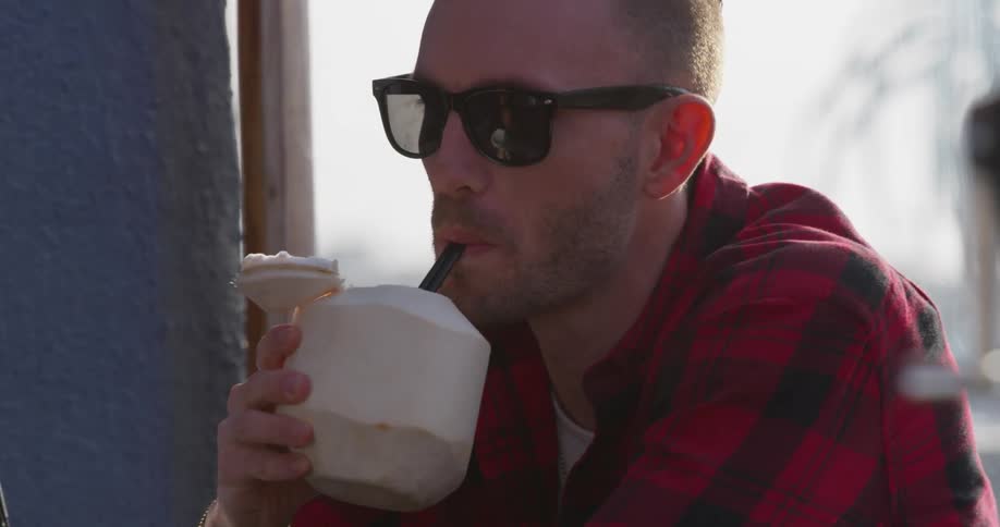 A man sips from a coconut