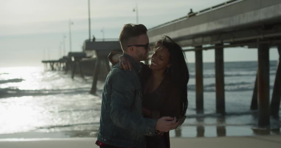 A man and woman take a photo together on the beach