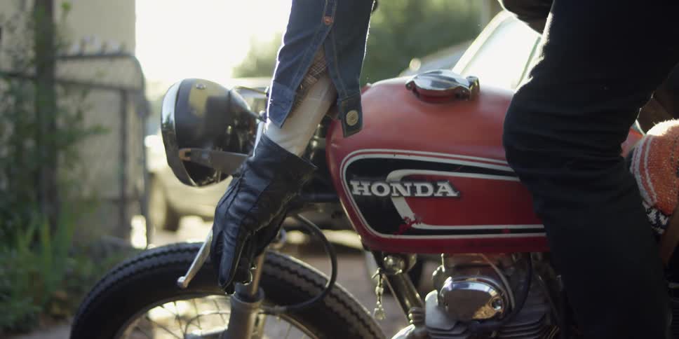A man starts a motorcycle on a sunny day