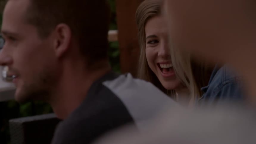 A man and two women, who are laughing, sit watching an event before them